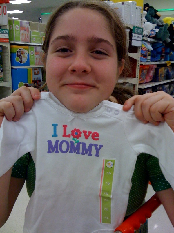 Image of a girl holding a baby's onesie that says "I love Mommy"