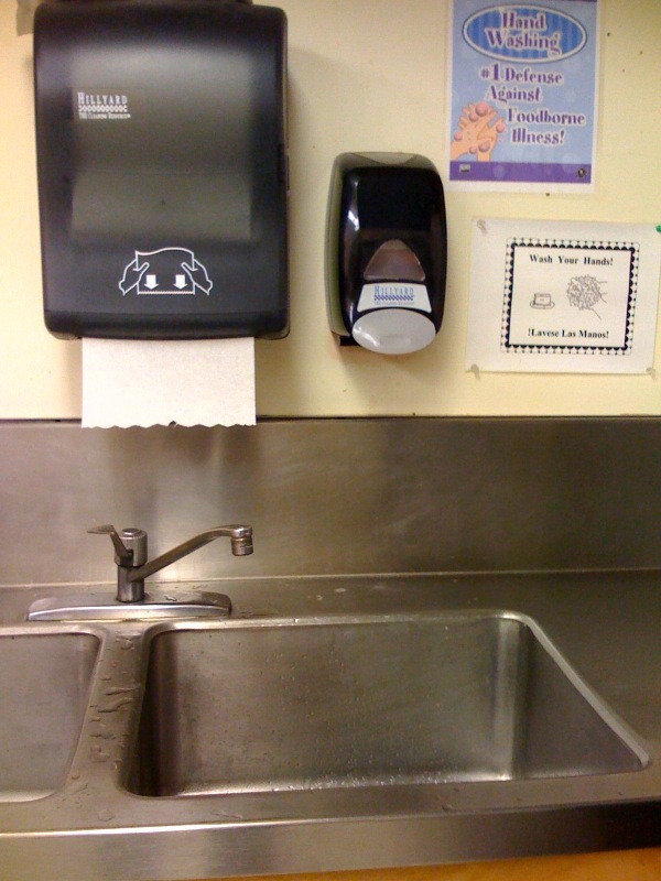 A picture of notices about handwashing, only visible behind the sink